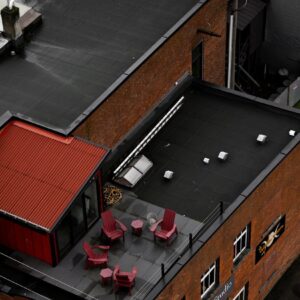 Rooftop patio with red chairs and tables.